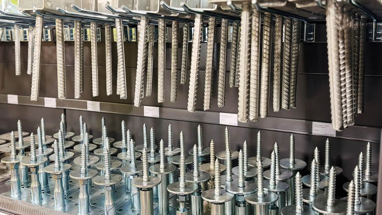 Regale voller Metall-Befestigungsmaterialien mit aufgehängten Stahlstäben und Schrauben.