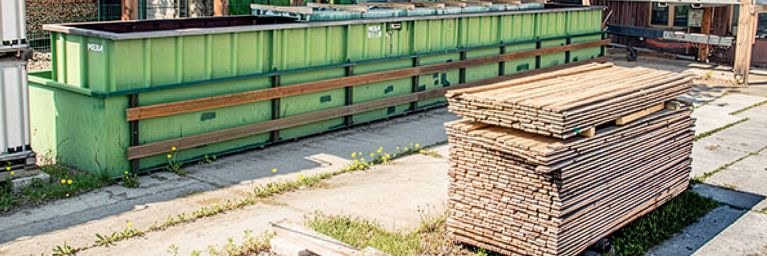 Mann überwacht große Holzbalken in einer industriellen Imprägnier-Anlage.